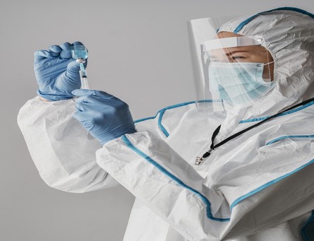 doctor-holding-vaccine-bottle-while-wearing-protective-equipment